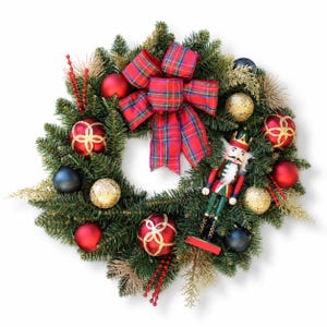 May include: A Christmas wreath made of green pine branches decorated with a red plaid bow, a wooden nutcracker figure, and various ornaments including matte red, dark blue, and gold glitter spheres, along with red berry sprigs.