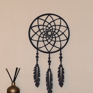Puede incluir: Decoración de pared de atrapasueños de metal negro con un diseño circular y tres plumas que cuelgan de la parte inferior.