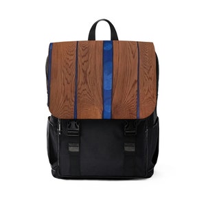 Puede incluir: Una mochila negra con un patrón de veta de madera marrón en la solapa delantera. La solapa tiene una franja azul en el centro.