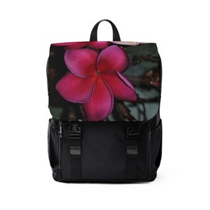 Puede incluir: Mochila negra con un diseño de flor rosa y blanca en la solapa delantera.