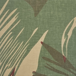 May include: Close-up of a camouflage fabric with a green, brown, and beige pattern. The fabric has a woven texture and a slightly faded appearance.