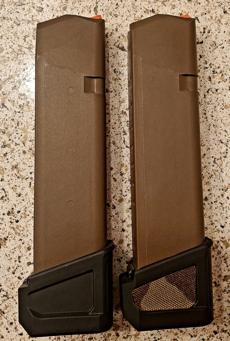 May include: Two brown magazine extensions for a firearm. The extension on the left has a black base, while the extension on the right has a brown camouflage base.