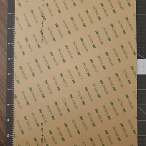 May include: A sheet of brown adhesive tape with a repeating pattern of green text that reads "3M 300LSE".