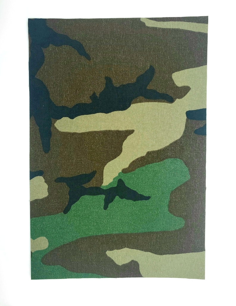 May include: Camouflage fabric with a green, brown, and black pattern. The fabric has a woven texture.