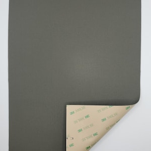 Puede incluir: Una hoja de tela gris oscuro con una superficie texturizada. La tela tiene un respaldo adhesivo marrón con el texto "3M 300LSE" impreso en él.