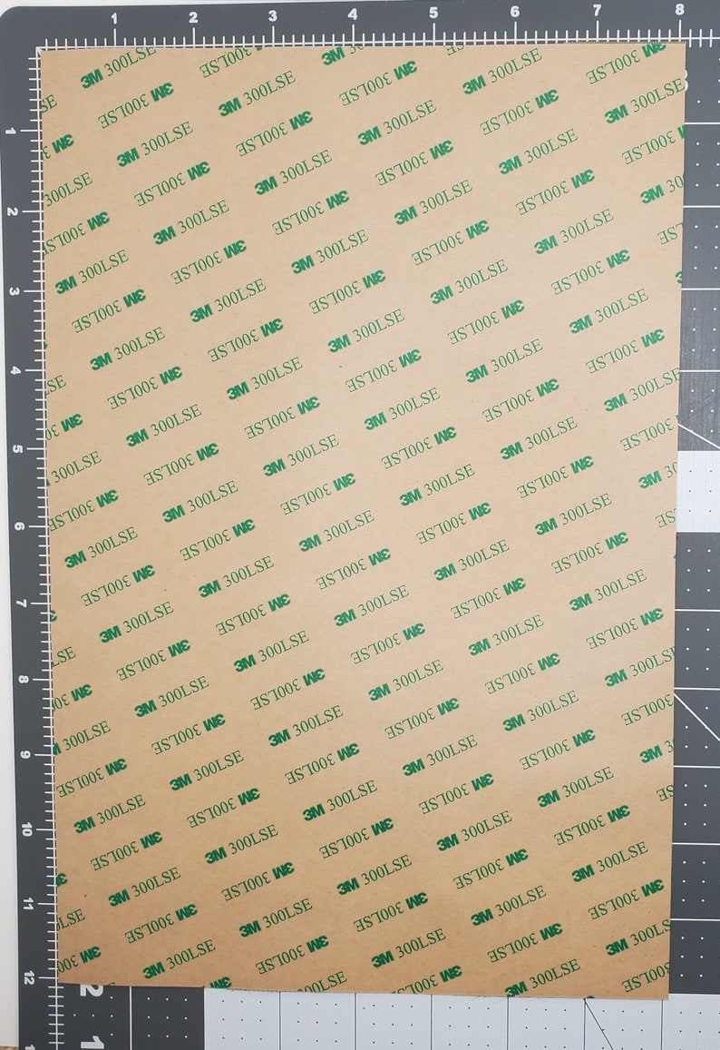 May include: A sheet of brown adhesive tape with a repeating pattern of green 3M 300LSE labels. The tape is marked with measurements in inches.