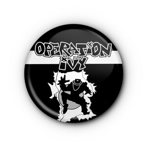 May include: A round, black and white button with the text "OPERATION IVY" in a stylized font. The button features a graphic of a figure breaking through a white background, with a black and white striped design.