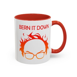 May include: White ceramic mug with a red interior and handle. The mug features the text "BERN IT DOWN" in red, above an orange and yellow graphic of a person's face with glasses and flames.