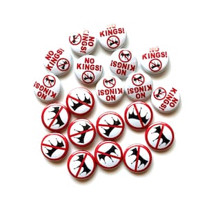 May include: A collection of white and red buttons with the text "NO KINGS!" and a crown symbol with a red slash through it. The buttons are round and have a pin backing.