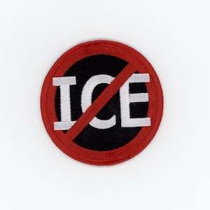 May include: A circular embroidered patch featuring a black background with the white text ICE in capital letters. A red border surrounds the circle, and a red diagonal line crosses through the center of the text, indicating a prohibition symbol.
