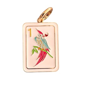 May include: A rectangular pendant with a gold-colored bail. The pendant features a parrot illustration with red, blue, and green details, perched on a branch. The number "1" is displayed in gold. The background is a light pink color.