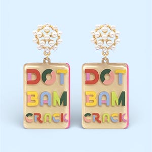 K&ouml;nnte beinhalten: Ein Paar goldfarbene Ohrringe mit rechteckigem Design. Jeder Ohrring zeigt die Worte "DOT BAM CRACK" in bunten Buchstaben. Die Oberseite jedes Ohrrings hat eine Ansammlung kleiner, wei&szlig;er Perlen.