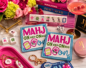 May include: Two square beaded coasters featuring the text MAHJ ON AND ON AND ON in bright pink, green, and blue beads. The design includes small mahjong tile motifs in yellow, pink, and white, all bordered by a blue beaded frame on a white background.