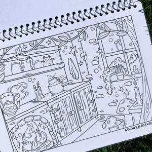 May include: Black and white illustration of a kitchen scene with a cat on a shelf, a fireplace, and a window with plants. The text "KINDR'D KITCH" is visible. The image is from a coloring book.