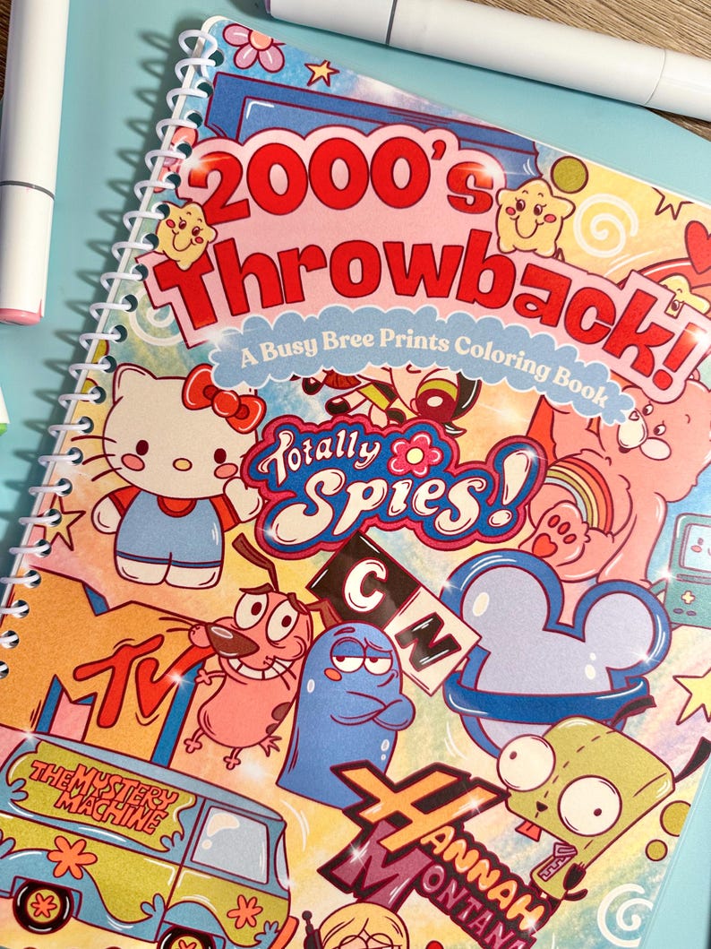 Puede incluir: Un libro para colorear con espiral titulado "2000's Throwback!" con personajes de dibujos animados como Hello Kitty, Coraje el perro cobarde y personajes de Totally Spies! y Hannah Montana. La portada es colorida con un fondo azul claro.