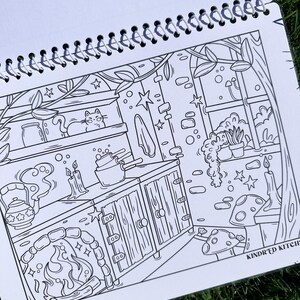 May include: Black and white illustration of a kitchen scene with a cat, candles, and a fireplace. The image is from a coloring book, with the text "KINDR'D KITCH" visible in the lower right corner.