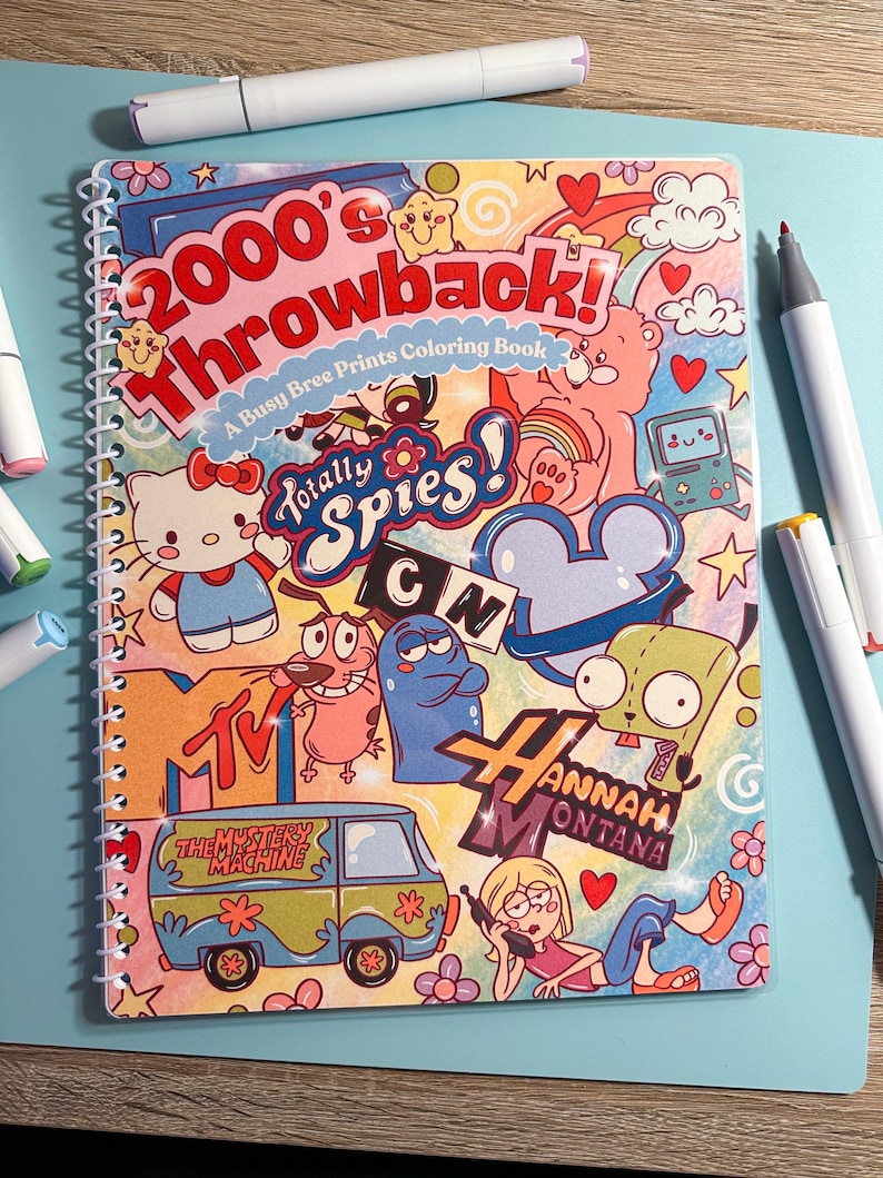 May include: A spiral-bound coloring book with a colorful cover featuring the text "2000's Throwback!" and various cartoon characters. The book is surrounded by several white markers with colored tips, set against a light blue surface.