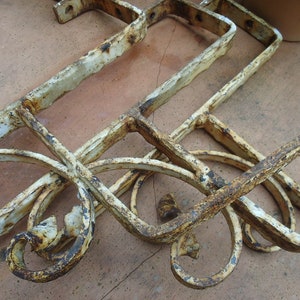 Puede incluir: Cuatro soportes metálicos oxidados con detalles de volutas ornamentadas. Los soportes son blancos con óxido que se ve a través.