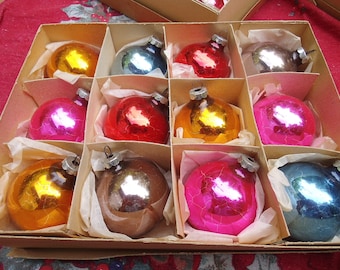 May include: A box of vintage Christmas ornaments in various colors, including red, gold, blue, pink, and silver. The ornaments are all round and have a shiny finish.