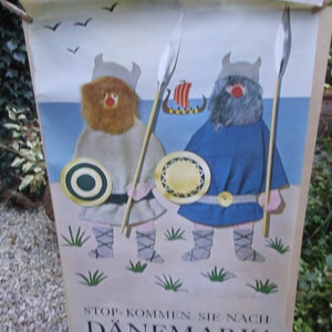 Könnte beinhalten: Ein Vintage-Reiseposter mit blauem Hintergrund, auf dem zwei Comic-Wikingerfiguren mit Speeren und Schilden zu sehen sind. Der Text auf dem Poster lautet "Stop - Kommen Sie nach Dänemark!" was mit "Stop - Kommen Sie nach Dänemark!" übersetzt werden kann.