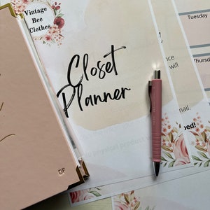 May include: A pink planner and pen rest on a table next to printed sheets. The planner has gold accents and the initials "DF". The sheets include the text "Closet Planner" and "Weekly Outfit Planner". Floral accents and the text "Vintage Bee Clothes" are also visible.