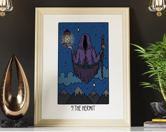 May include: A framed print of a tarot card titled 9. THE HERMIT. The illustration features a hooded figure in a purple robe floating above mountains, holding a glowing lantern in one hand and a wooden staff in the other against a starry blue sky.