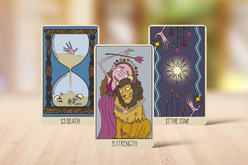 May include: Three tarot cards featuring illustrated designs. The left card shows an hourglass with skulls and a hand, labeled 13 DEATH. The center card depicts a figure embracing a lion, labeled 8 STRENGTH. The right card shows a star, labeled 17 THE STAR.