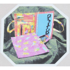 May include: A yellow and red striped fabric pencil case with a blue zippered pocket and a pink fabric pouch with a white and yellow pattern. The pencil case has a blue notebook with the word "Attitude" written on it.