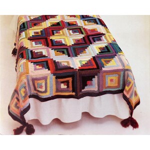 May include: A colorful, handmade crochet blanket with a patchwork design. The blanket features squares in various colors, including red, blue, yellow, and purple. The edges are finished with a dark border and tassels. The blanket is draped over a bed.
