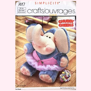 May include: A Simplicity crafts/ouvrages pattern for making a plush elephant toy. The elephant is wearing a pink tutu and has a bouquet of flowers in its trunk. The pattern is titled "Chubby Cheeks" and is number 7417.