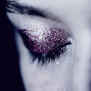 Op de afbeelding: Close-up van een oog met roze glitter oogschaduw en lange wimpers.