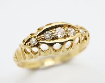 Op de afbeelding: Een gouden ring met een delicaat ontwerp met vijf heldere edelstenen in een rij. De ring heeft een getextureerde band met opengewerkte details.