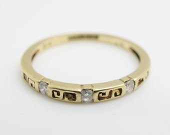 Op de afbeelding: Een gouden ring met een herhalend Grieks sleutelmotief en kleine heldere stenen die in de band zijn gezet.