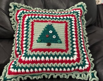 May include: A green, red, and white crocheted pillow with a Christmas tree design. The tree is decorated with buttons and a star.