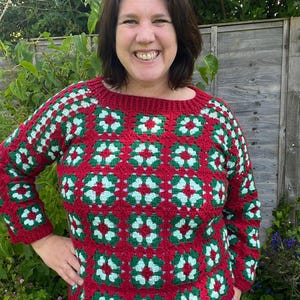 May include: A red and green crocheted sweater with a square pattern. The sweater has a crew neck and long sleeves.