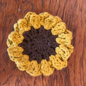 K&ouml;nnte beinhalten: Eine geh&auml;kelte Sonnenblume mit brauner Mitte und gelben Bl&uuml;tenbl&auml;ttern.