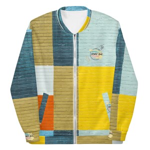 May include: A full-zip bomber jacket with a colorful brick wall pattern. The jacket features a mix of blue, yellow, orange, and tan rectangular shapes. The text "OOOZ INK" is printed on the jacket. The jacket has a white interior lining.
