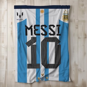 May include: A white and light blue soccer jersey with the name "MESSI" and the number "10" printed on the front. The jersey has the Argentinian national team logo on the right side and the Adidas logo on the left side.