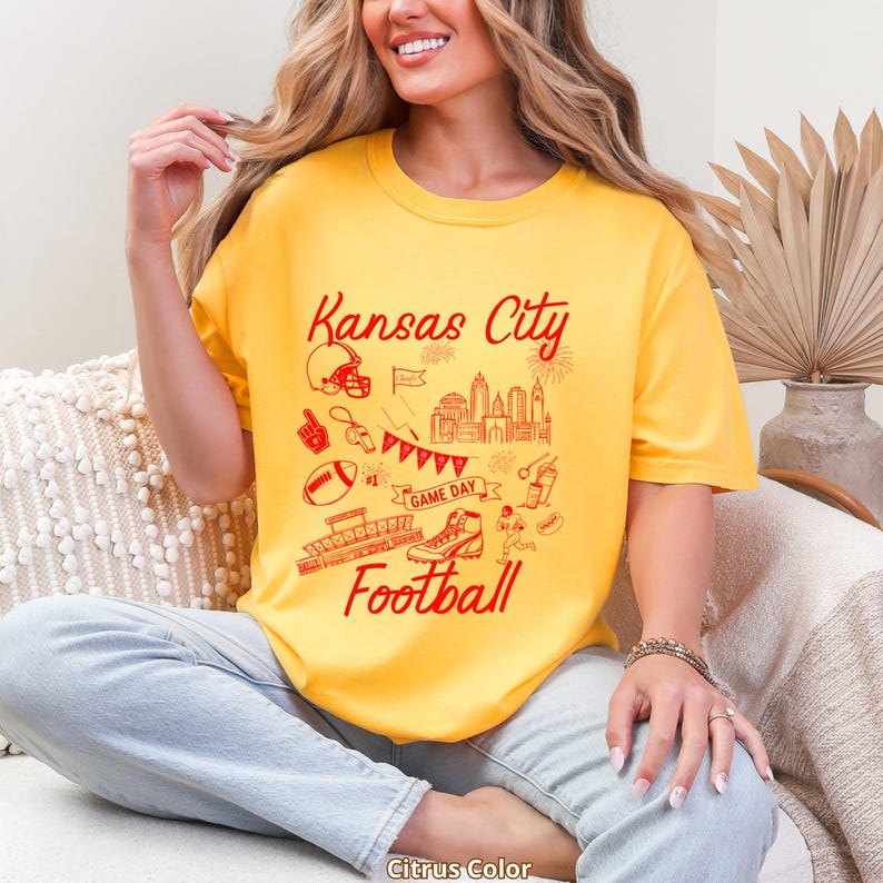 May include: A yellow t-shirt with a red graphic design featuring the words "Kansas City Football" and various football-related illustrations. The shirt is a citrus color.