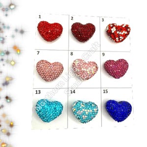 May include: Assortment of 15 heart-shaped rhinestone embellishments in various colors, including red, pink, blue, and turquoise. Each heart is approximately 1 inch in size.