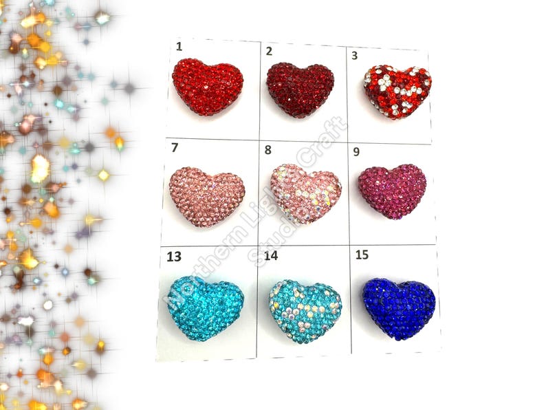 May include: Assortment of 15 heart-shaped rhinestone embellishments in various colors, including red, pink, blue, and turquoise. Each heart is approximately 1 inch in size.