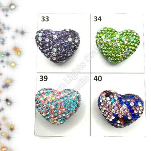 May include: Four heart-shaped rhinestone embellishments in different colors: purple, green, pink, and blue. The rhinestones are arranged in a grid pattern on a white background. The numbers 33, 34, 39, and 40 are printed above each embellishment.