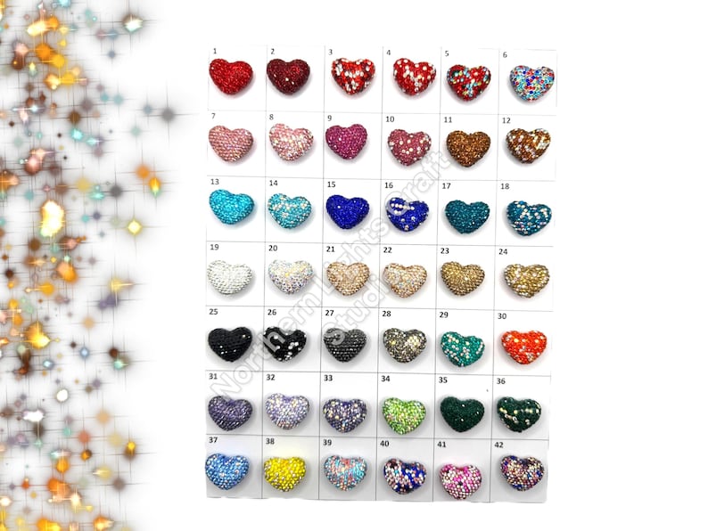 May include: Assortment of 42 heart-shaped rhinestone embellishments in various colors, including red, blue, green, gold, and silver. Each heart is approximately 1 inch in diameter.
