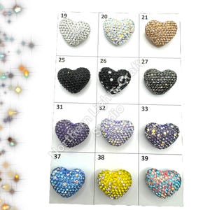 May include: Assortment of 10 heart-shaped rhinestone embellishments in various colors, including silver, gold, black, blue, purple, and yellow. Each heart is approximately 1 inch in size.