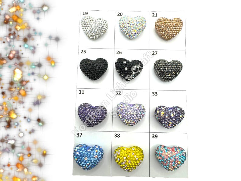 May include: Assortment of 10 heart-shaped rhinestone embellishments in various colors, including silver, gold, black, blue, purple, and yellow. Each heart is approximately 1 inch in size.