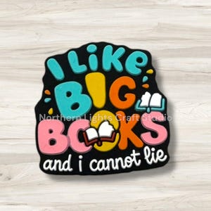 May include: A black, irregular-shaped decorative item with the text "I like BIG BOOKS and I cannot lie." The text is in various colors, including blue, orange, pink, and yellow. The words "BIG BOOKS" are the largest. The item also features an open book graphic.