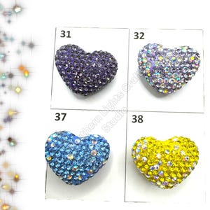 May include: Four heart-shaped rhinestone embellishments in different colors: purple, light blue, and yellow. The embellishments are arranged in a grid with numbers 31, 32, 37, and 38 above each one.