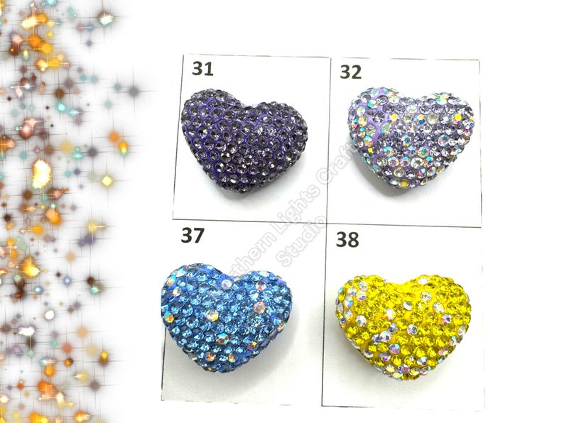 May include: Four heart-shaped rhinestone embellishments in different colors: purple, light blue, and yellow. The embellishments are arranged in a grid with numbers 31, 32, 37, and 38 above each one.