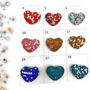 May include: Assortment of 10 heart-shaped rhinestone embellishments in various colors, including red, blue, green, brown, and pink. Each heart is approximately 1 inch in size.