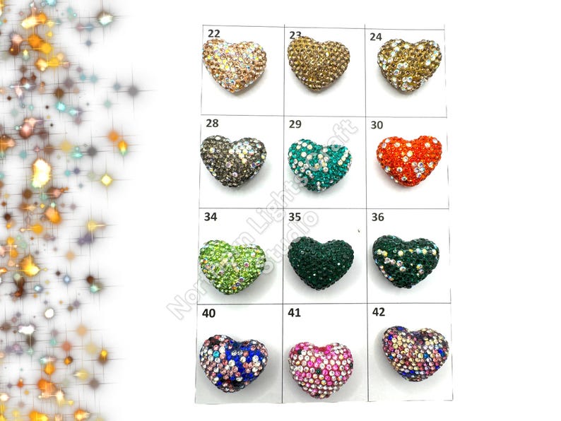 May include: Assortment of 10 heart-shaped rhinestone embellishments in various colors, including gold, silver, green, blue, red, and pink. Each heart is numbered 22 through 42.
